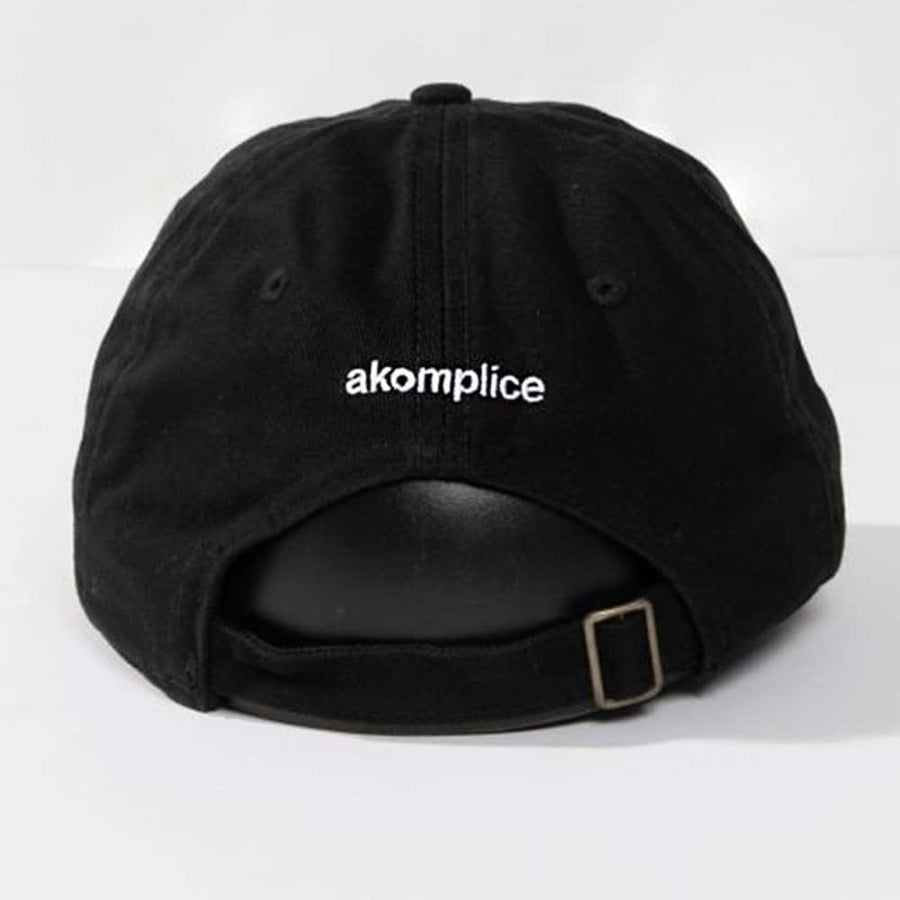 Black cap with 'akomplice' logo on a white background