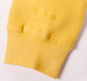 Yellow sweatshirt with a brand logo on a light gray background