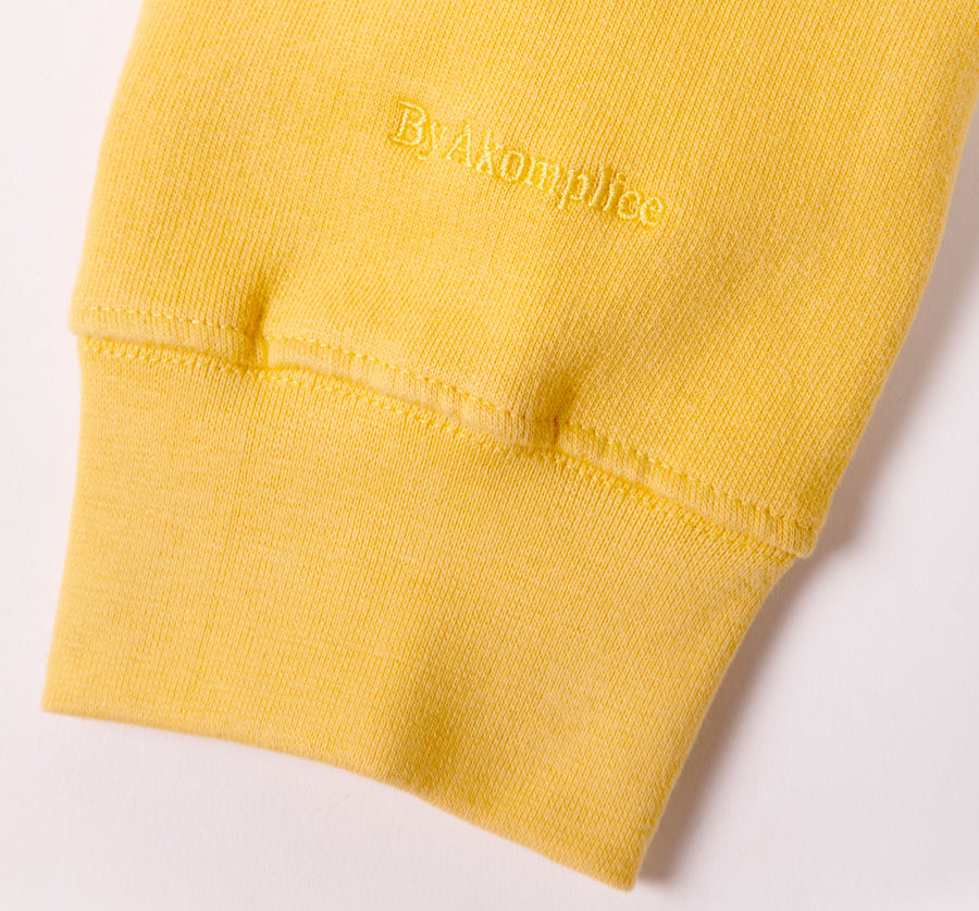 Yellow sweatshirt with a brand logo on a light gray background
