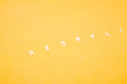 Text 'AKOMPLI' on a yellow background