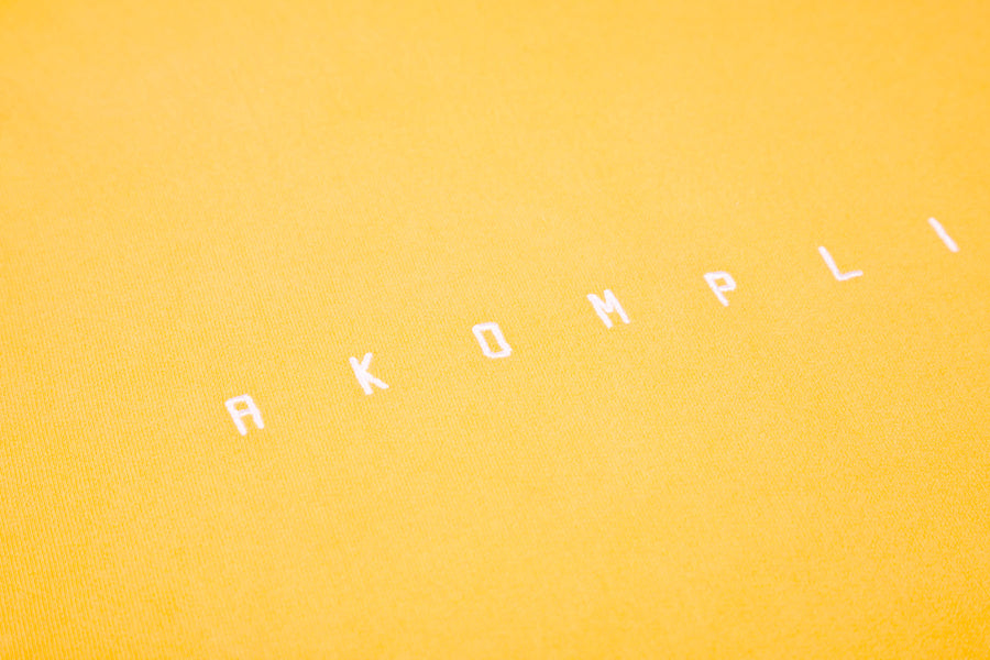 Text 'AKOMPLI' on a yellow background