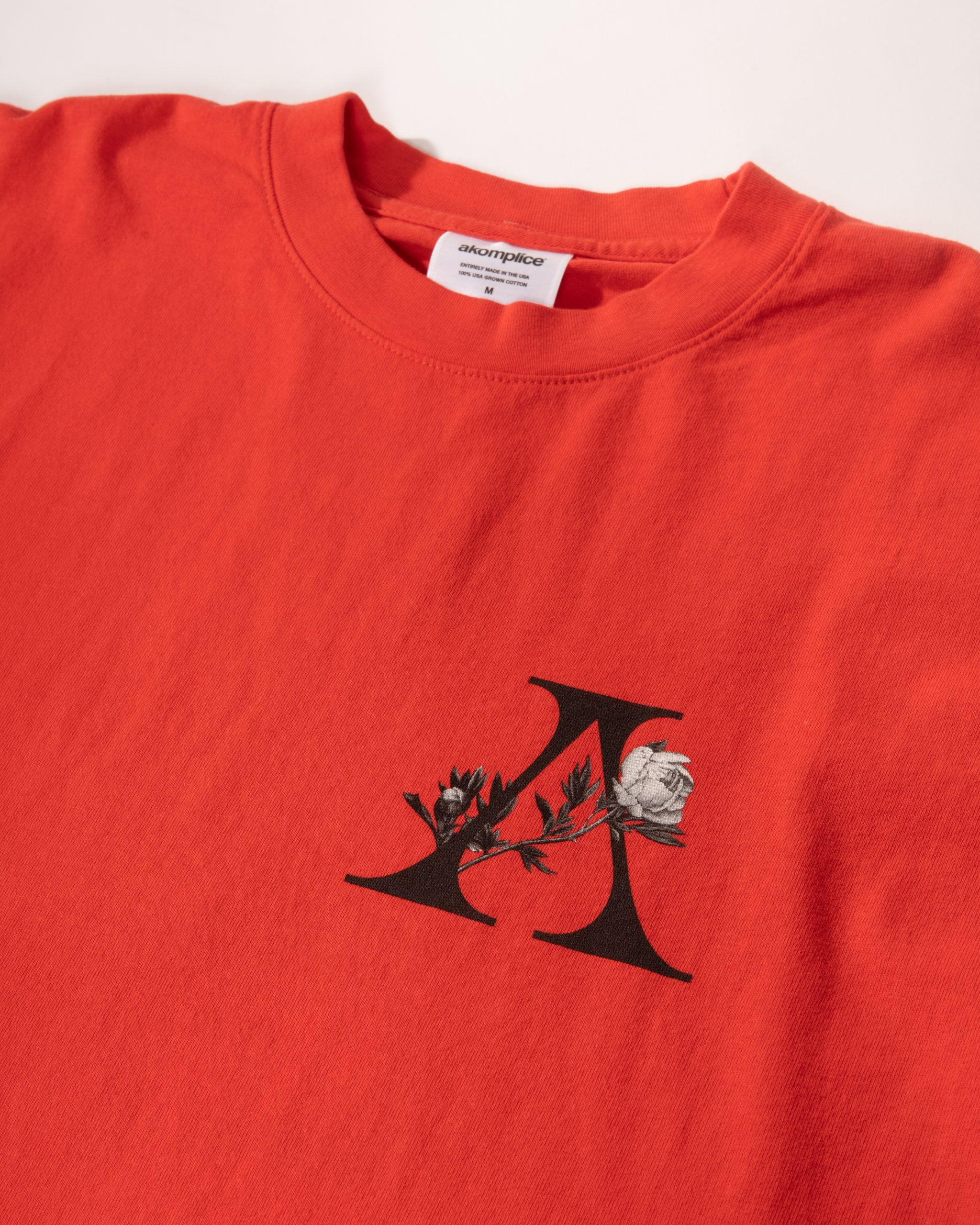 Red sweatshirt with a black and white logo featuring a rose and deer on a white background