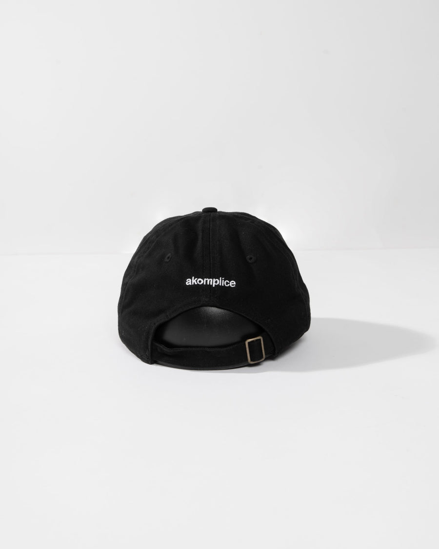 Black cap with 'akomplice' logo on a white background