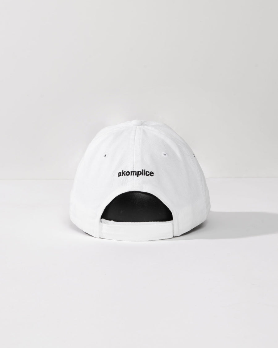 White cap with 'akomplice' logo on a white background