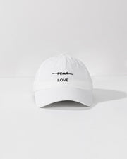 White cap with 'FEAR LOVE' text on a white background