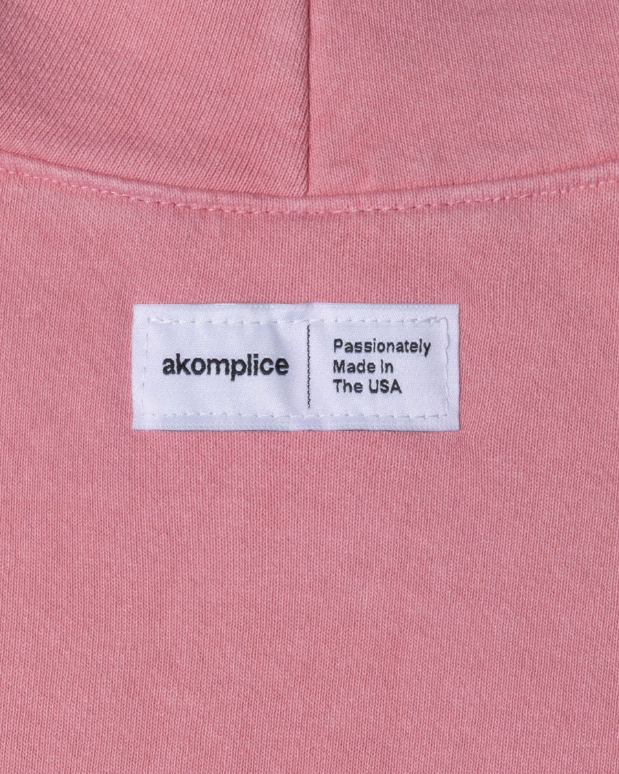 Close-up of a pink fabric with an 'akomplice' label on it.