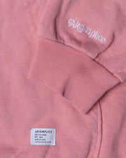 Close-up of a pink sweatshirt with 'Akompllice' branding on the sleeve and label.