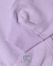 Close-up of a lavender hoodie with 'Akomplice' branding on the chest pocket and label.