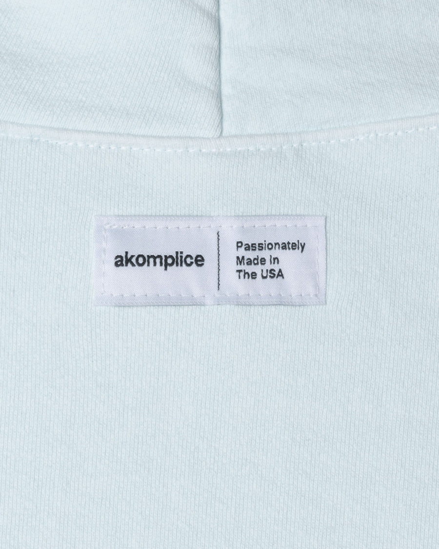 Light blue fabric with a label reading 'akomplice Passionately Made in The USA'.