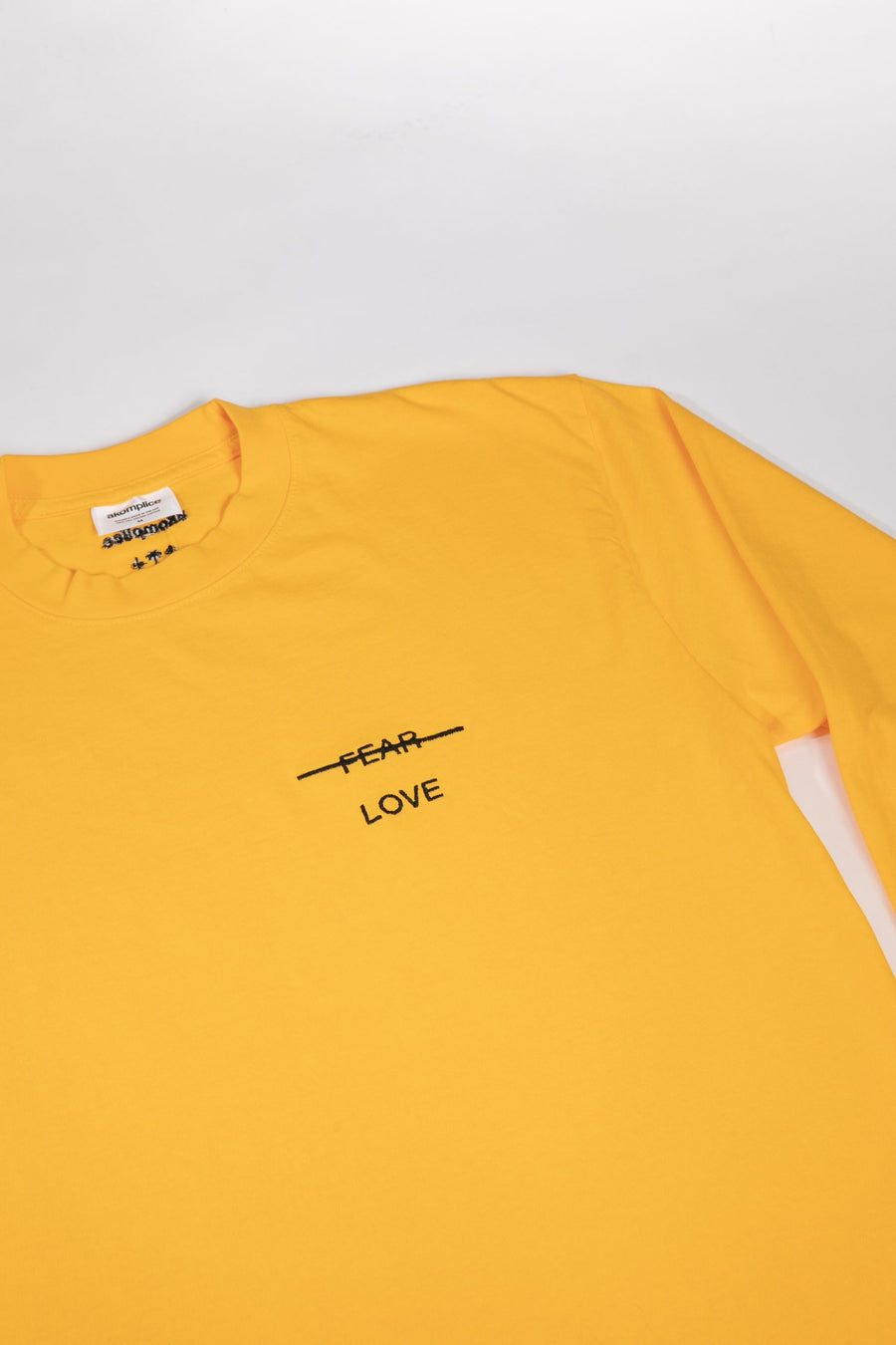 Yellow t-shirt with 'FEAR LOVE' text on a light gray background