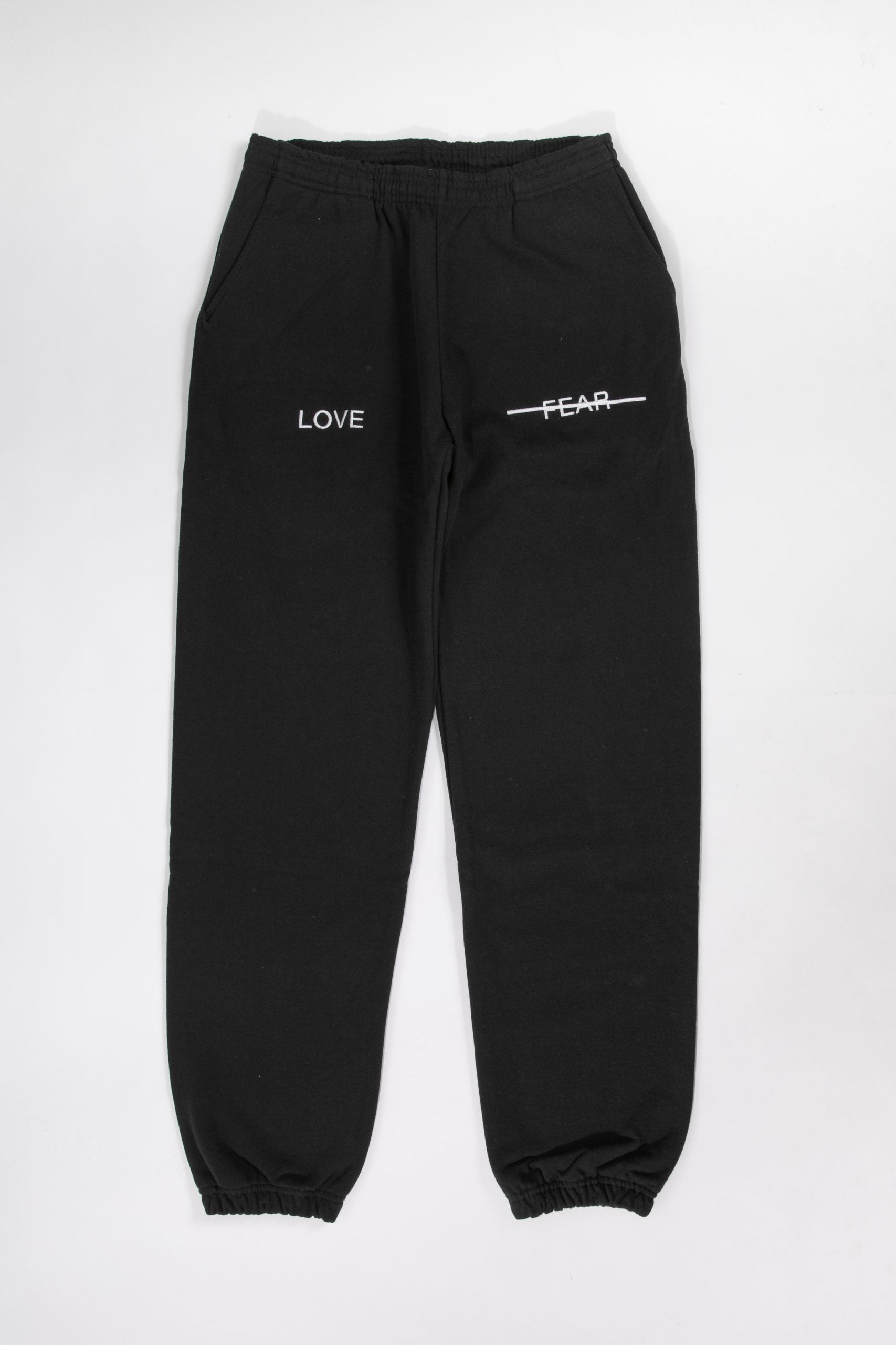 Black sweatpants with 'LOVE' and 'FEAR' text on a white background