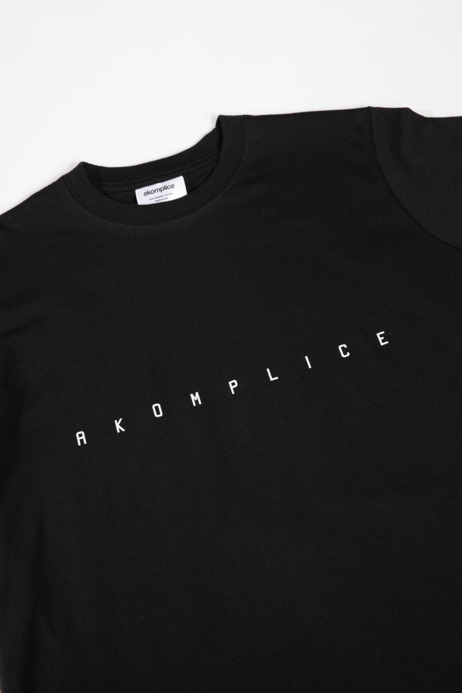 Black t-shirt with 'AKOMPLICE' text on a white background