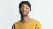 Man wearing a black beanie and yellow shirt against a white background