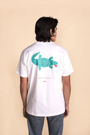 Person wearing a white t-shirt with a green alligator graphic on the back against a beige background