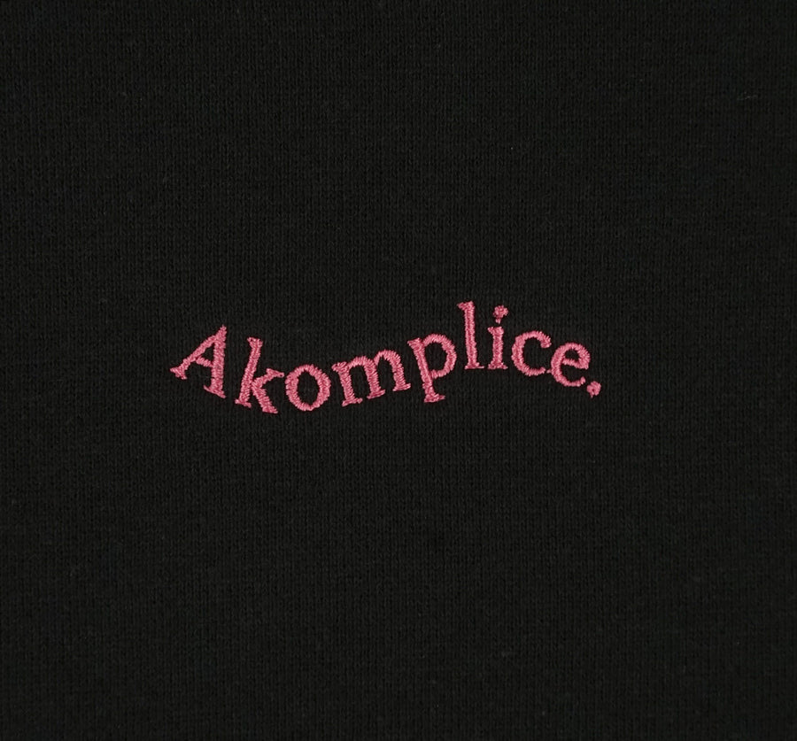 Pink Akomplice Logo on black background