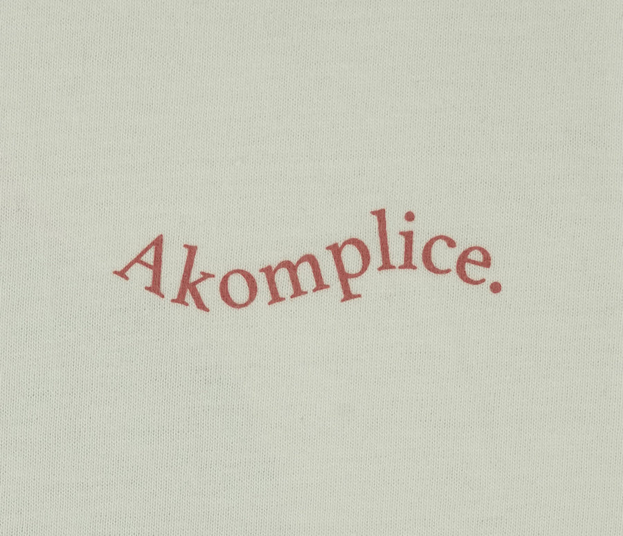 Text 'Akomplice' in red on a beige background