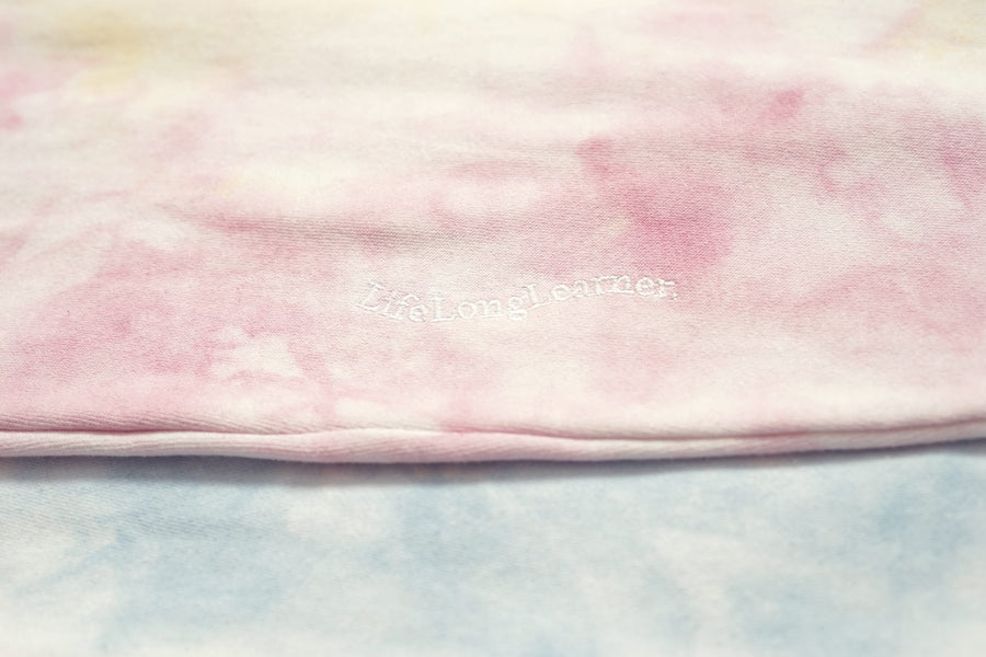 Pink and white tie-dye fabric with 'Gildan' branding on a light blue background