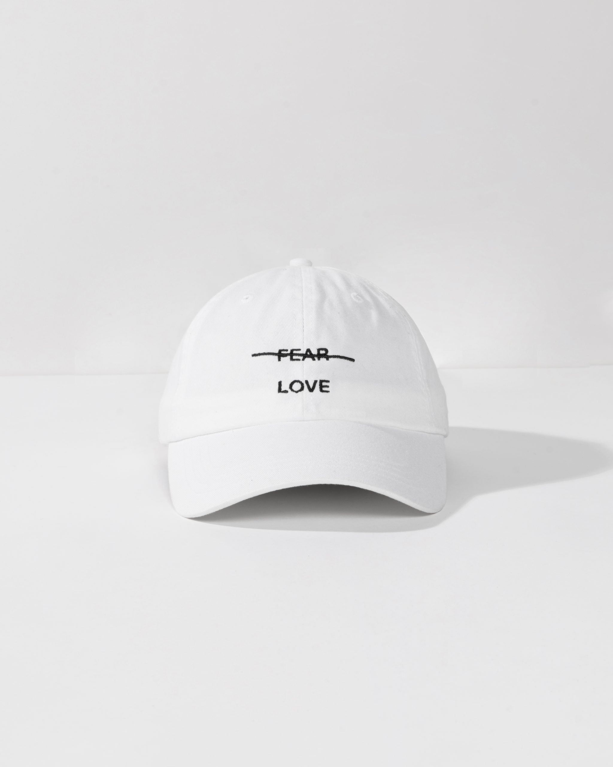 White cap with 'FEAR LOVE' text on a white background