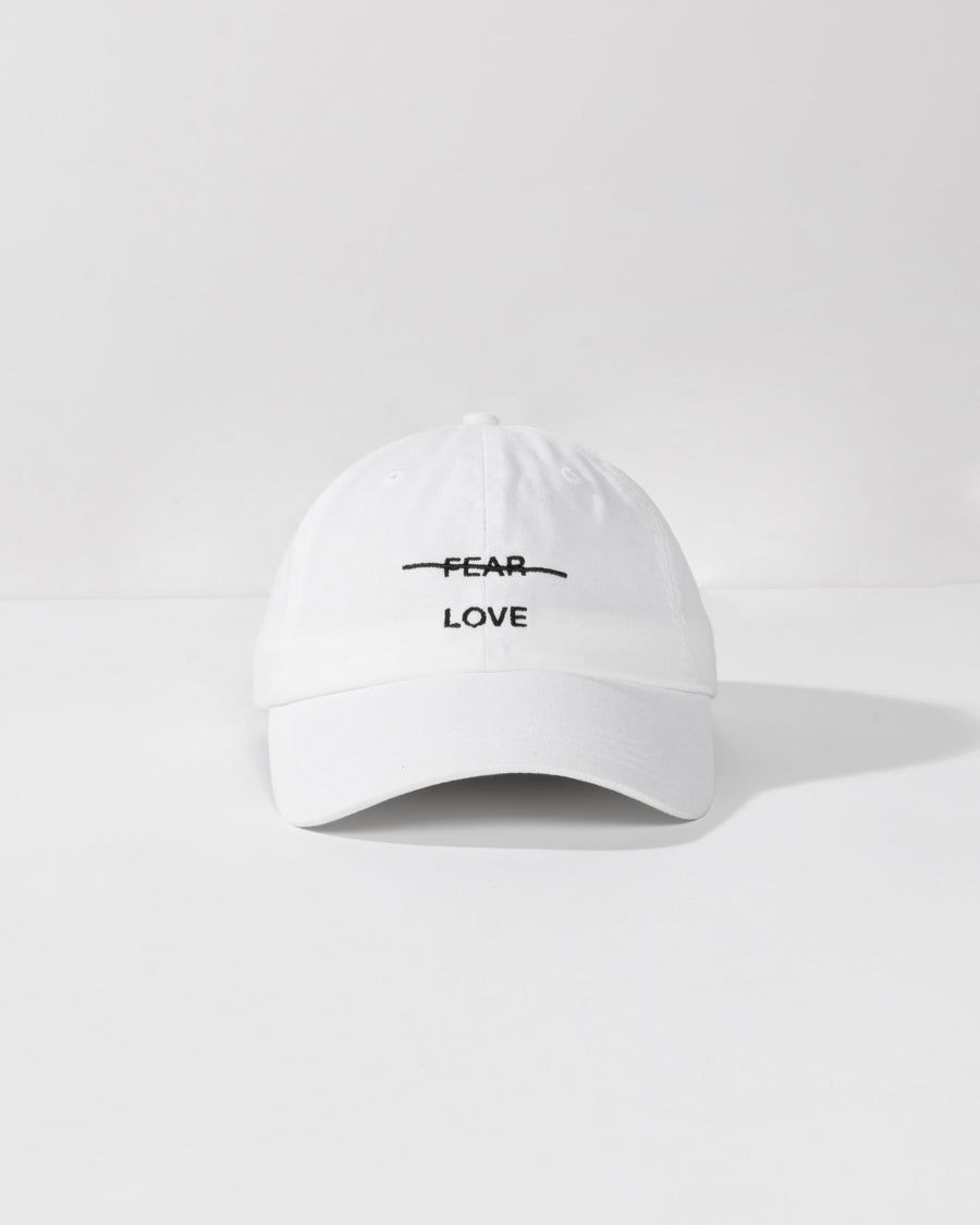 White cap with 'FEAR LOVE' text on a white background