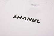 White t-shirt with 'SHANEL' printed in black on a white background