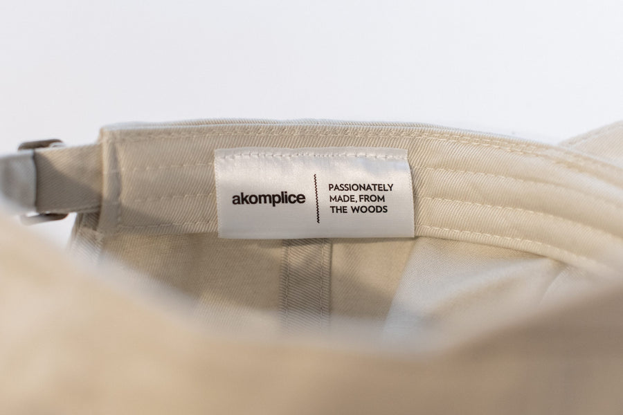 Beige bag with 'akomplice' label on a white background