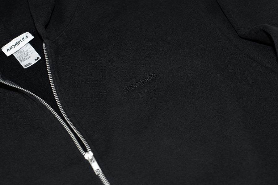 Close-up of a black hoodie with a zipper and brand label.