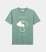 Green t-shirt with white mushroom graphic and 'AKOMPLICE' text on a light gray background
