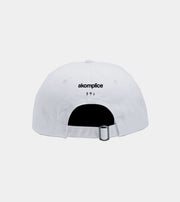 White cap with 'akomplice' logo on a light gray background