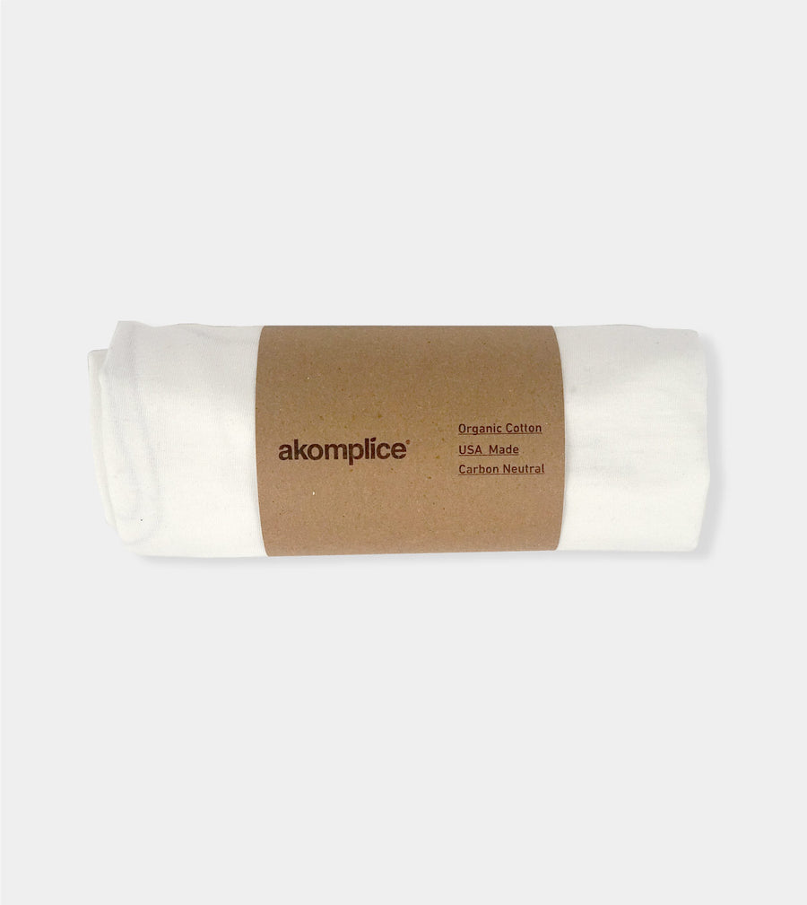 Roll of organic cotton fabric with 'akomplice' label on a white background