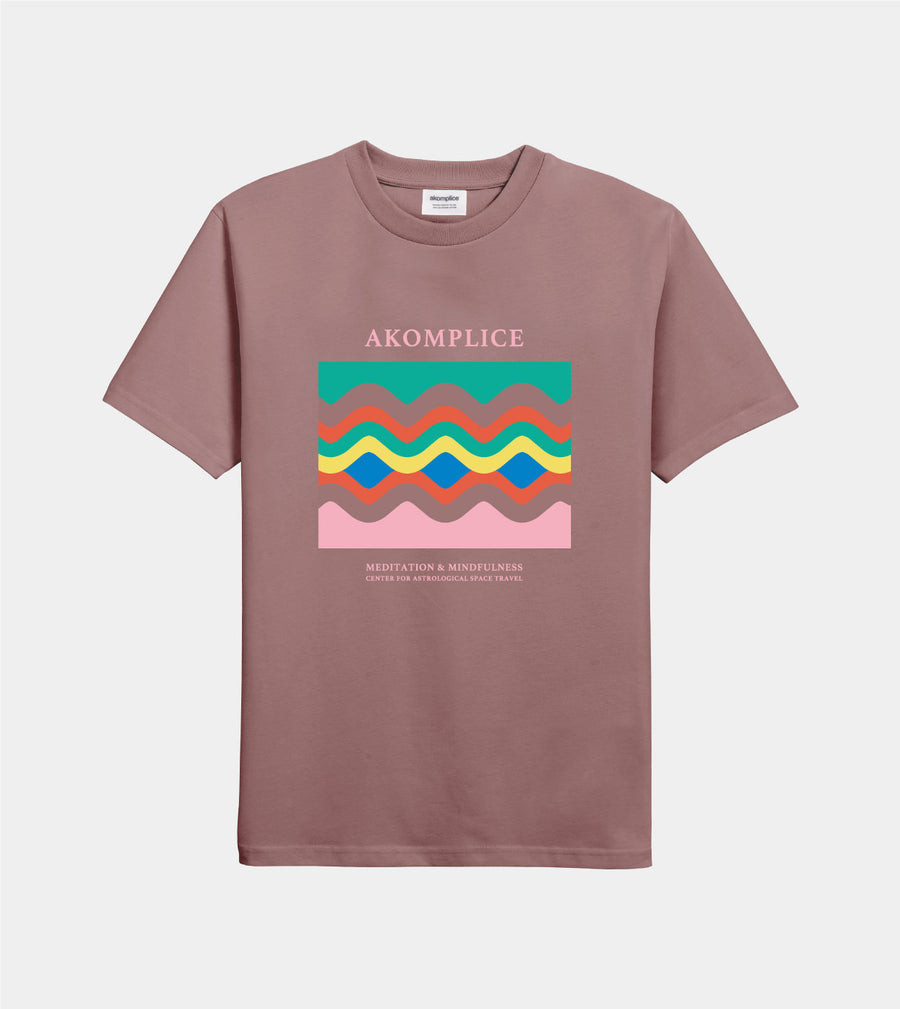 Brown t-shirt with colorful graphic and 'AKOMPLICE' branding on a light gray background