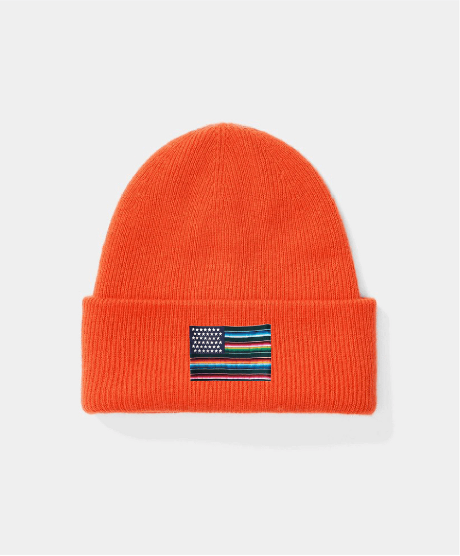 Orange beanie with a small flag patch on a light gray background