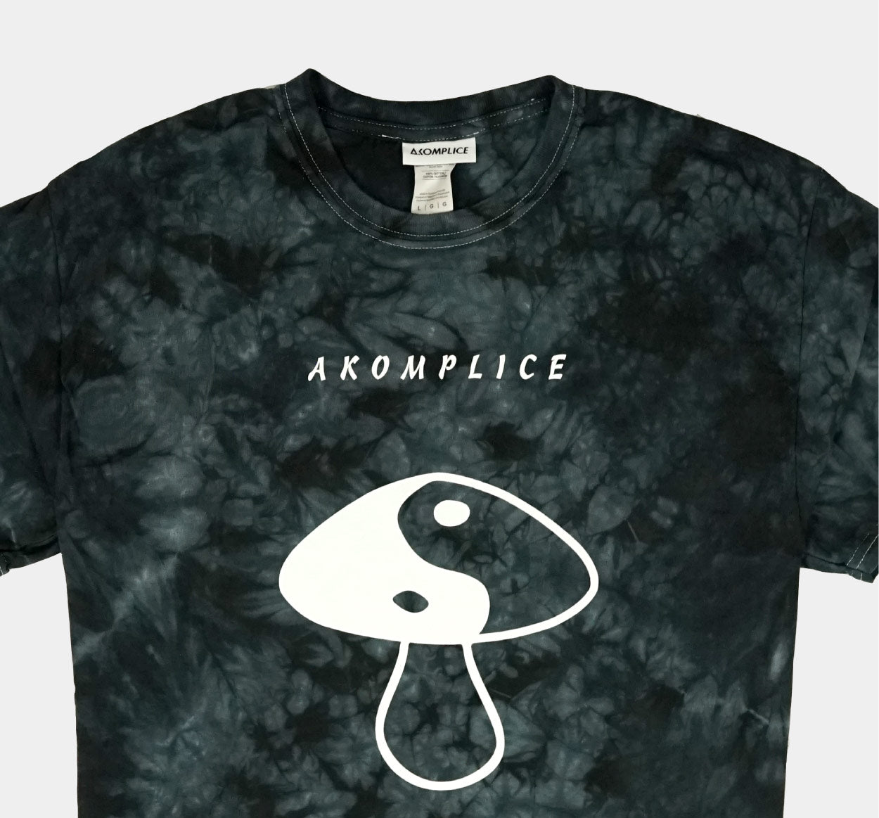 Tie-dye t-shirt with 'Akomplice' logo and mushroom graphic on a plain background